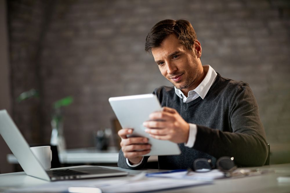 Homem analisando informações em um tablet, simbolizando o processo de captação de investimentos com um investidor-anjo.