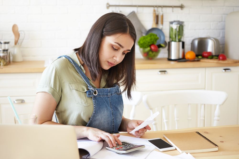 Mulher calculando seus ganhos e custos enquanto considera as taxas da Shopee para vender online com maior controle financeiro